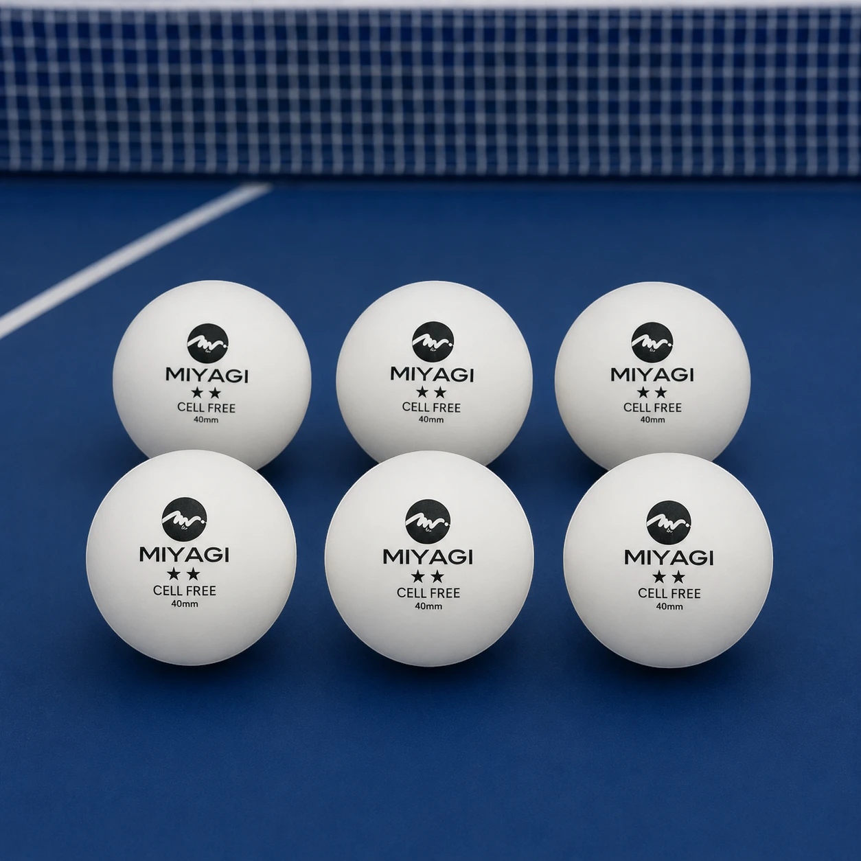 Seis bolas Miyagi Tournament 2 estrellas blancas organizadas sobre mesa de tenis